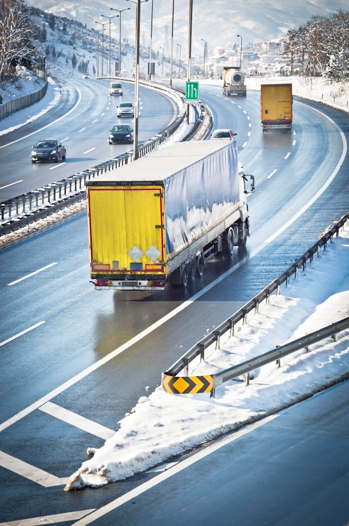 Highway scene with trucks and cars driving on a snowy winter day.